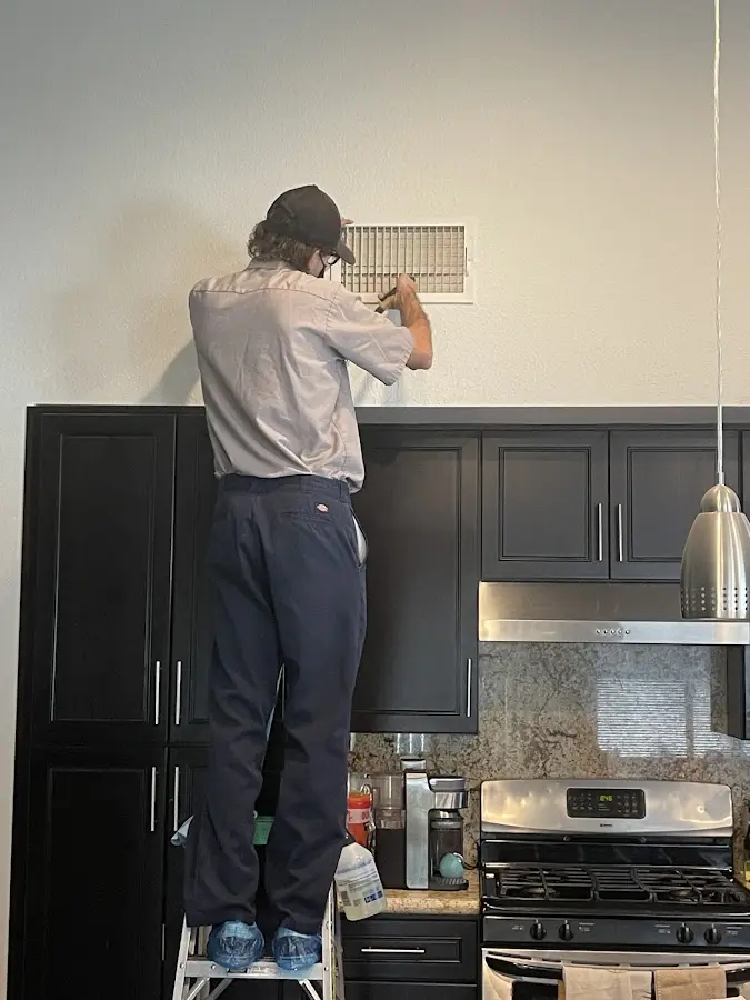 Technician inspecting an air vent during HVAC service in Fort Pierce